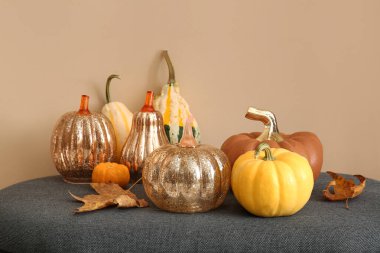 Sonbahar yapraklı balkabakları bej duvarın yanında, yakın plan.