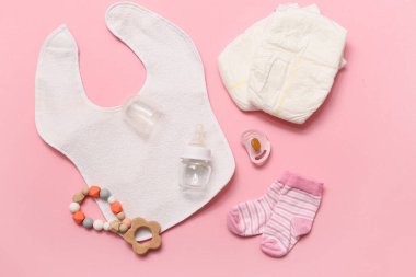 Pembe arka planda bebek şişesi ve aksesuarları olan kompozisyon