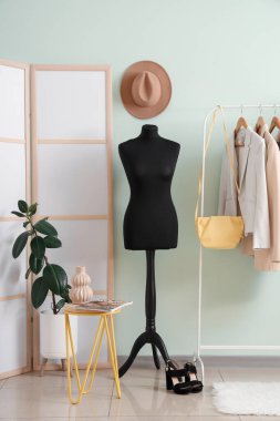 Manken, katlanan perde ve elbise askısı olan soyunma odasının içinde.