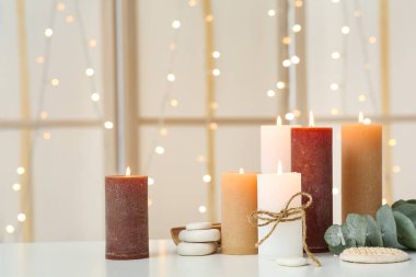 Işık arka planında yanan mumlar ve spa taşları