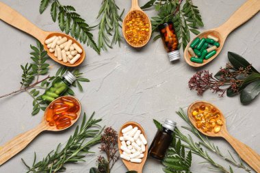 Farklı haplardan yapılmış çerçeve ve gri arka planda taze otlar