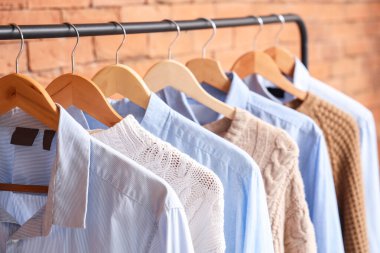 Tuğla duvarın yanında kazak ve gömlekler var. Yakın çekim.