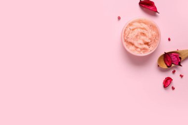 Doğal vücut fırçası kavanozu ve pembe arka planda çiçek yaprakları olan kompozisyon