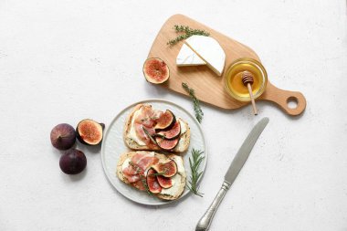 Beyaz arka planda prosciutto ve ricotta peynirli lezzetli incirli bruschetta tabağı.