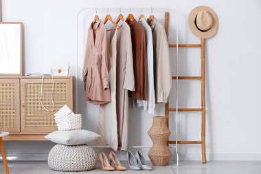 Beyaz duvarın yanında elbise askısı, merdiven ve şifoniyeri olan modern soyunma odasının içinde.