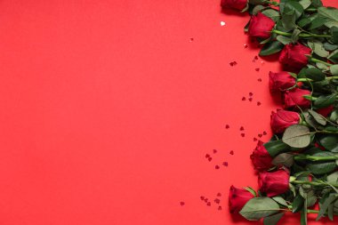 Güzel gül çiçekleri ve kırmızı arka planda kalp şeklinde pulları olan kompozisyon. Sevgililer Günü kutlaması