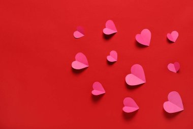 Kırmızı zemin üzerinde kağıt kalpler olan kompozisyon. Sevgililer Günü.