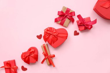 Pembe arka planda Sevgililer Günü kutlaması için farklı hediye kutuları ve kalplerle kompozisyon