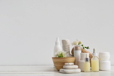 Spa aksesuarları, kozmetik ürünleri ve açık ahşap masa üzerinde çiçekler içeren kompozisyon