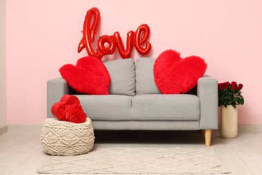Oturma odasının içi Sevgililer Günü için koltuk, puf ve balonla dekore edilmiş.