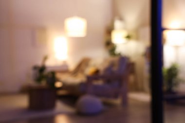 Rahat bir kanepe, kahve masası ve geceleri oturma odasının içinde parlayan lambalar. Bulanık görünüm