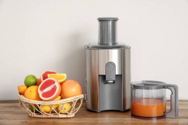 Beyaz duvarın yanındaki masada taze narenciye ve meyve suyu sepeti.