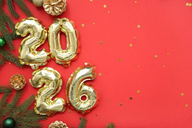 Noel topları, çam kozalakları ve kırmızı arka planda köknar dalları olan folyodan yapılmış 2025 yılı figürü.