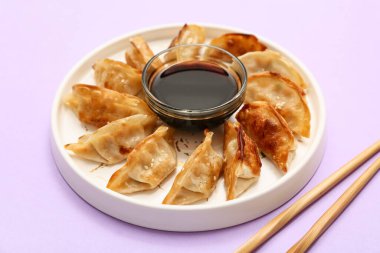 Kızarmış Japon gyoza tabağı ve leylak arkaplanda soya sosu.