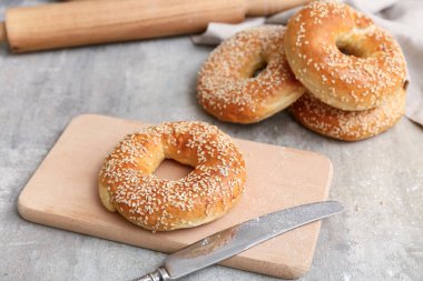 Gri arka planda susam tohumlu ahşap simit tahtası, yakın plan.