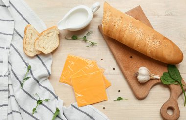 Lezzetli işlenmiş peynir dilimleri ve beyaz ahşap masada taze ekmek.
