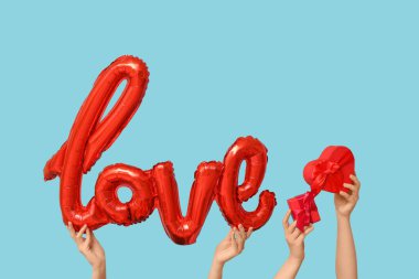 Balon şekilli kadın elleri ve mavi arka planda hediye kutuları. Sevgililer Günü kutlaması