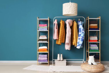 Kışlık giysiler ve mavi duvarın yanındaki raf üniteleriyle doldur.