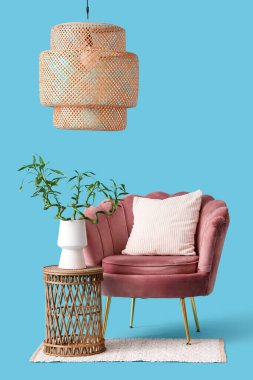 Vazoda bambu saplı masa, koltuk, halı ve lamba mavi arka planda.