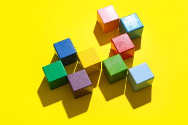 Sarı zemin üzerinde renkli yapı küpleri olan kompozisyon