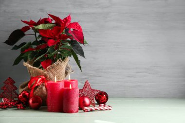 Güzel Noel çiçekleri, dekorasyonlar ve yanan mumlar açık ahşap masada.