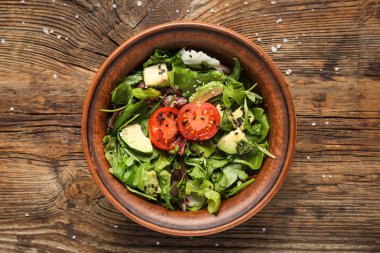 Çeri domatesli avokado salatası ve ahşap zemin üzerinde susam tohumları.