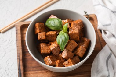 Beyaz arka planda kızarmış tofu peyniri ve fesleğenli kase, yakın plan.