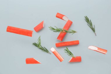 Gri arka planda uçuşan lezzetli yengeç çubukları ve biberiye