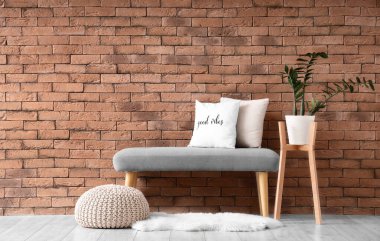 Odadaki tuğla duvarın yanında yumuşak bir bank ve puf.