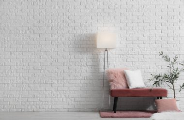 Oda içinde pembe bank, lamba ve zeytin ağacı var.