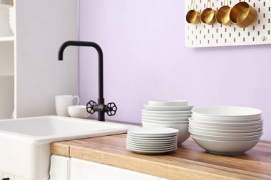 Temiz tabaklar ve kaseler şık mutfaktaki lavabonun yanında, yakın plan.