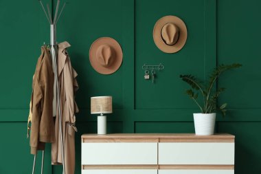 Çekmeceli, elbise askısı ve yeşil duvarlı şık bir salon.