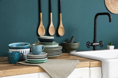 Mutfakta mavi duvarın yanında farklı tabaklar olan tahta masa.