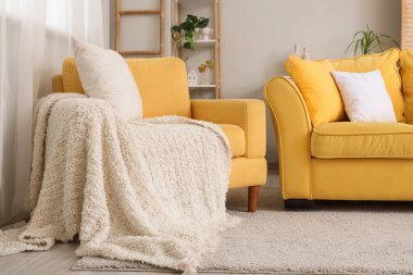 Şık bir oturma odası, rahat sarı koltuğu ve kanepesi var.