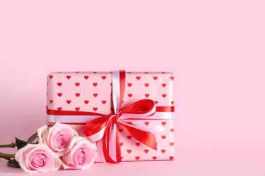 Gül çiçekli kompozisyon ve pembe arka planda hediye kutusu. Sevgililer Günü kutlaması.