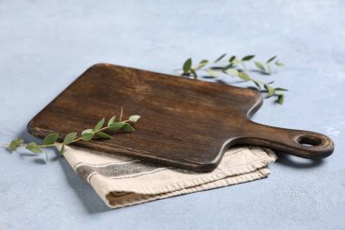 Boş kesme tahtası peçete ve okaliptüs yaprakları mavi grunge masasında, yakın plan