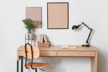 Ahşap masası, şık masa lambası ve evde kitapları olan modern çalışma alanı.