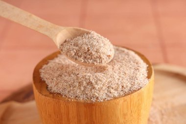 Masanın üzerinde Psyllium kabuğu tozu olan kase ve kaşık, yakın plan.