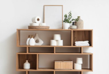 Tuvalet kağıdı ruloları ve kozmetik ürünleri banyodaki raf ünitesinde.