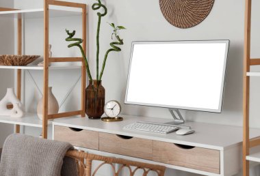 Beyaz duvarın yanındaki masada bilgisayar ve alarmlı çalışma odası, yakın plan.