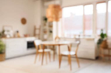 Yemek masası, tezgah ve bitkilerle aydınlık mutfağın bulanık görüntüsü