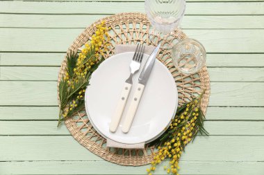 Yeşil ahşap arka planda mimoza çiçekleri olan güzel bir masa.