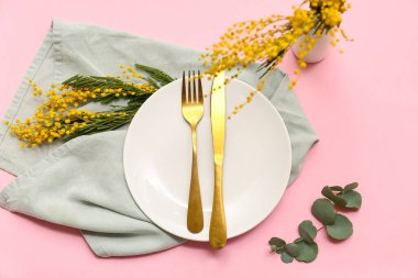 Mimoza çiçekleri ve pembe arka planda okaliptüs olan güzel bir masa.