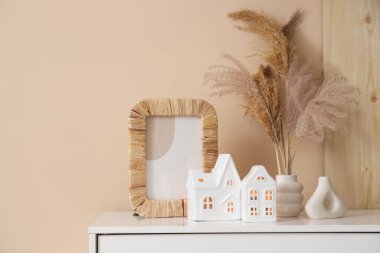 Odadaki bej duvarın yanındaki çekmecelerde, fotoğraf çerçevesi ve ev şeklinde mum tutacakları.