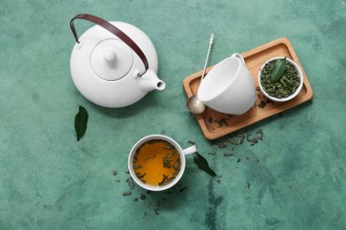 Çaydanlık ve bir fincan sıcak yeşil çay. Arka planda kurumuş yapraklar var.