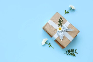 Hediye kurdelesi ve mavi arka planda papatya çiçeğiyle bağlanmış bir yığın kitap.