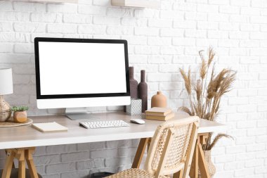 Beyaz tuğla duvarın yanında modern bilgisayar ve pampa çimleriyle şık çalışma alanı