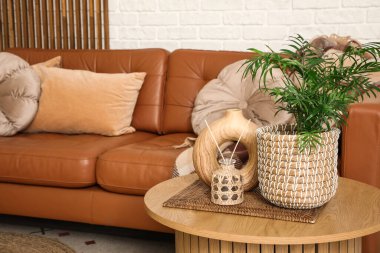 Masa ve deri kahverengi kanepe oturma odasının iç tarafındaki beyaz tuğla duvarın yanında.