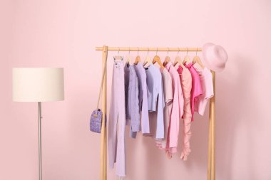 Pembe duvarın yanında şık kıyafetler ve lambayla dizilin.