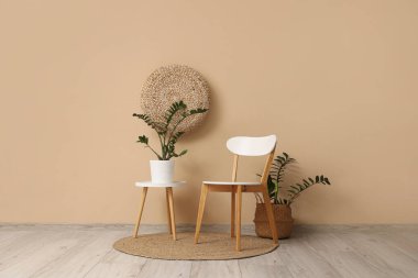 Bej duvarın yanında sandalye, masa ve ev bitkileriyle modern tarz bir oda.